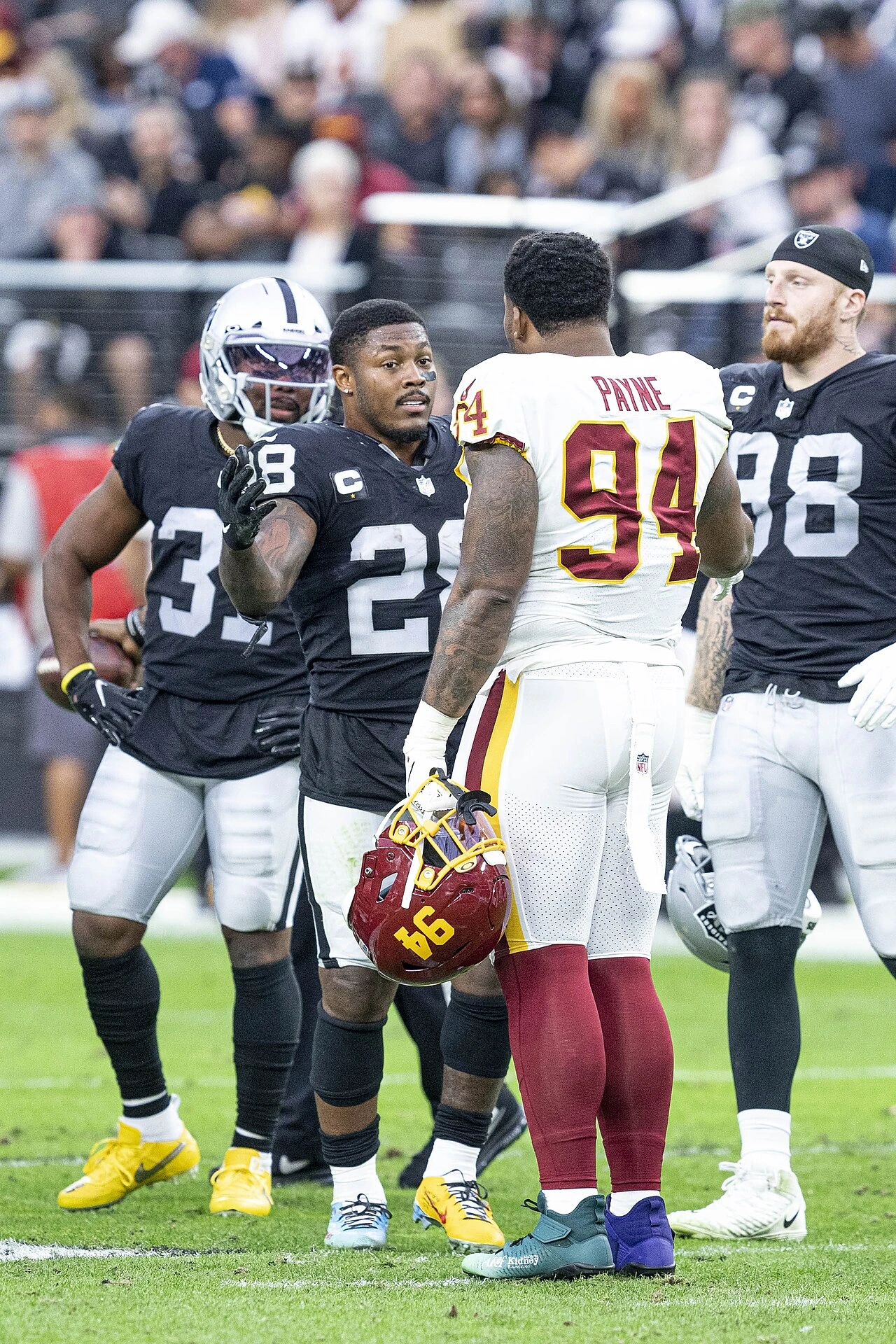 Josh Jacobs with teammates on the field after a Las Vegas Raiders game
